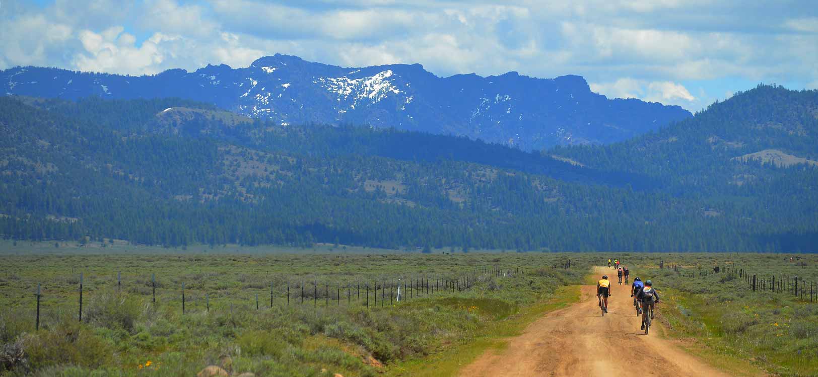 Riders on dirt road in broad alpine valley